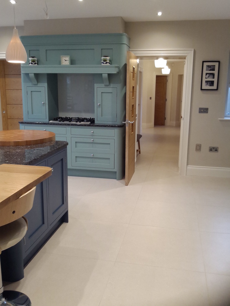 Mittelgroße Klassische Wohnküche mit blauen Schränken, Granit-Arbeitsplatte, Küchenrückwand in Weiß, Porzellan-Bodenfliesen und Kücheninsel in Belfast