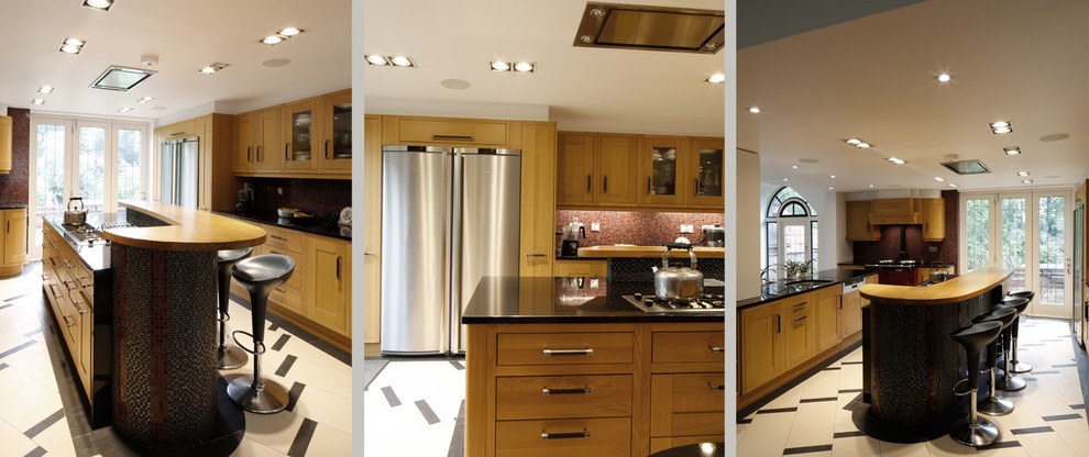 Large classic galley kitchen/diner in London with a single-bowl sink, recessed-panel cabinets, medium wood cabinets, marble worktops, red splashback, ceramic splashback, stainless steel appliances, ceramic flooring, an island, beige floors and black worktops.
