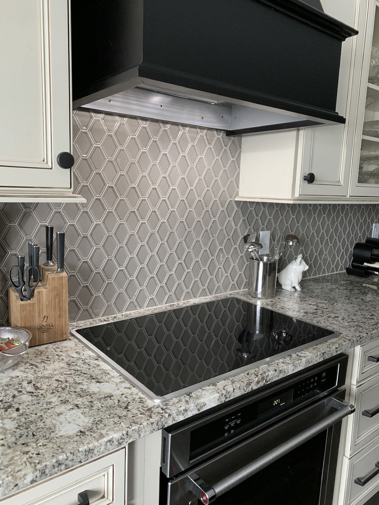 Exempel på ett stort klassiskt flerfärgad flerfärgat kök, med en undermonterad diskho, luckor med infälld panel, vita skåp, granitbänkskiva, grått stänkskydd, stänkskydd i keramik, rostfria vitvaror och en köksö