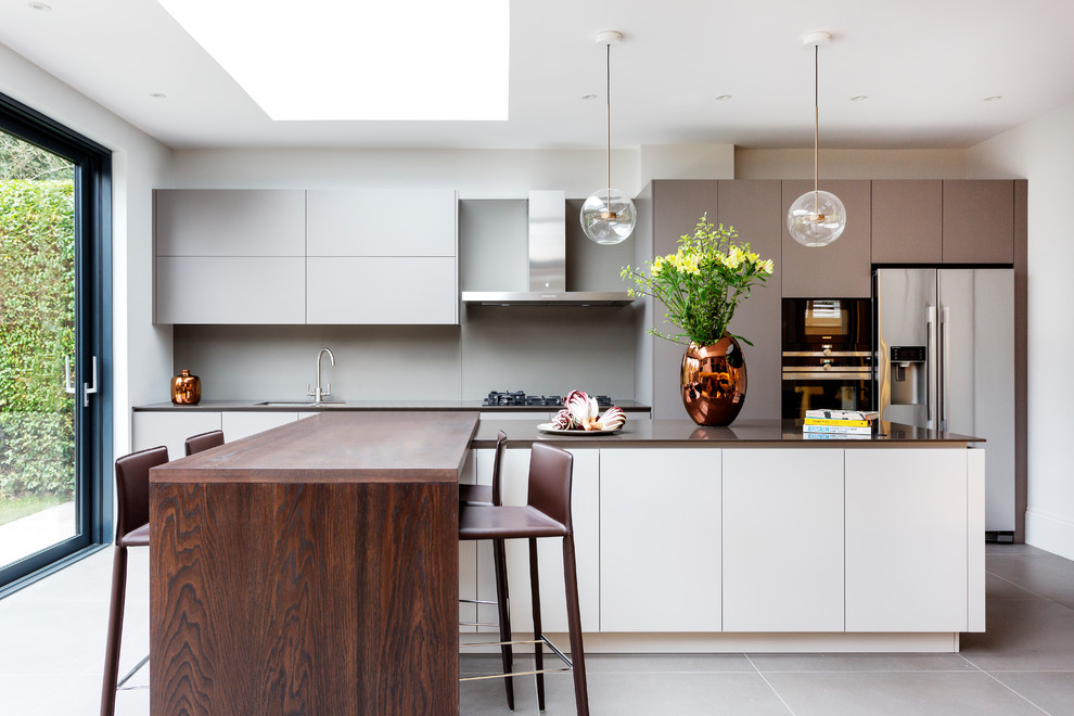 Design ideas for a medium sized contemporary single-wall kitchen in London with a submerged sink, flat-panel cabinets, grey splashback, stainless steel appliances, grey floors, grey cabinets, multiple islands and brown worktops.
