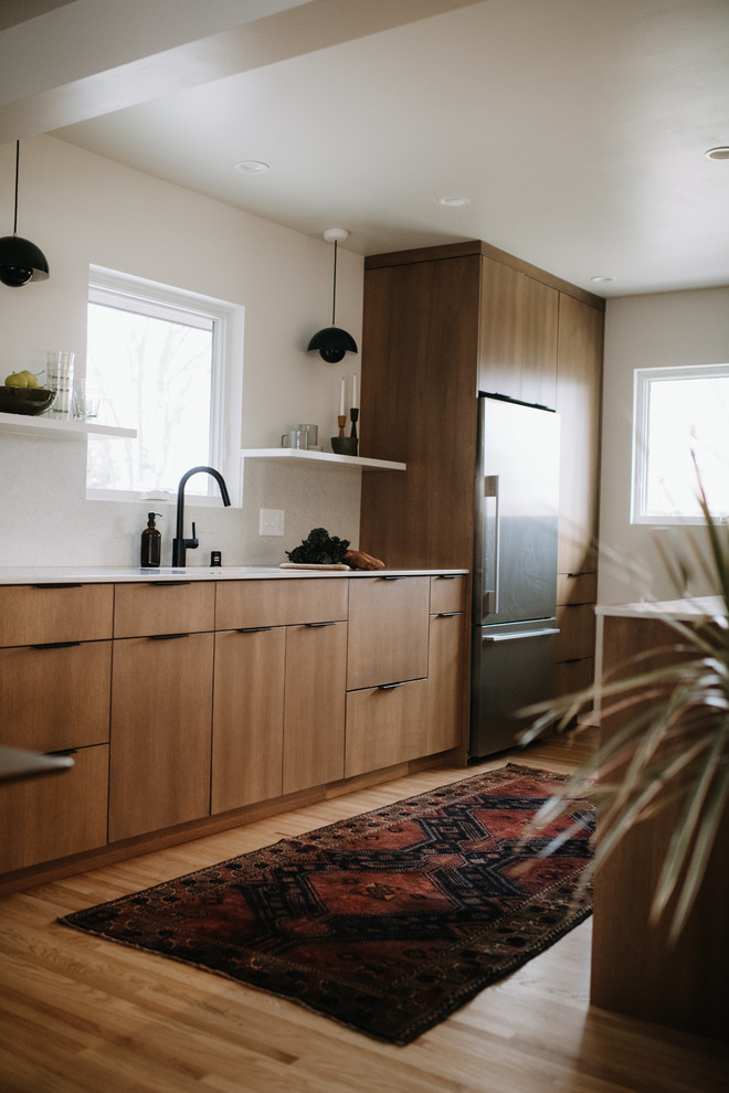 Scandi kitchen/diner in Minneapolis with a submerged sink, flat-panel cabinets, light wood cabinets, engineered stone countertops, white splashback, stainless steel appliances, light hardwood flooring, no island and white worktops.