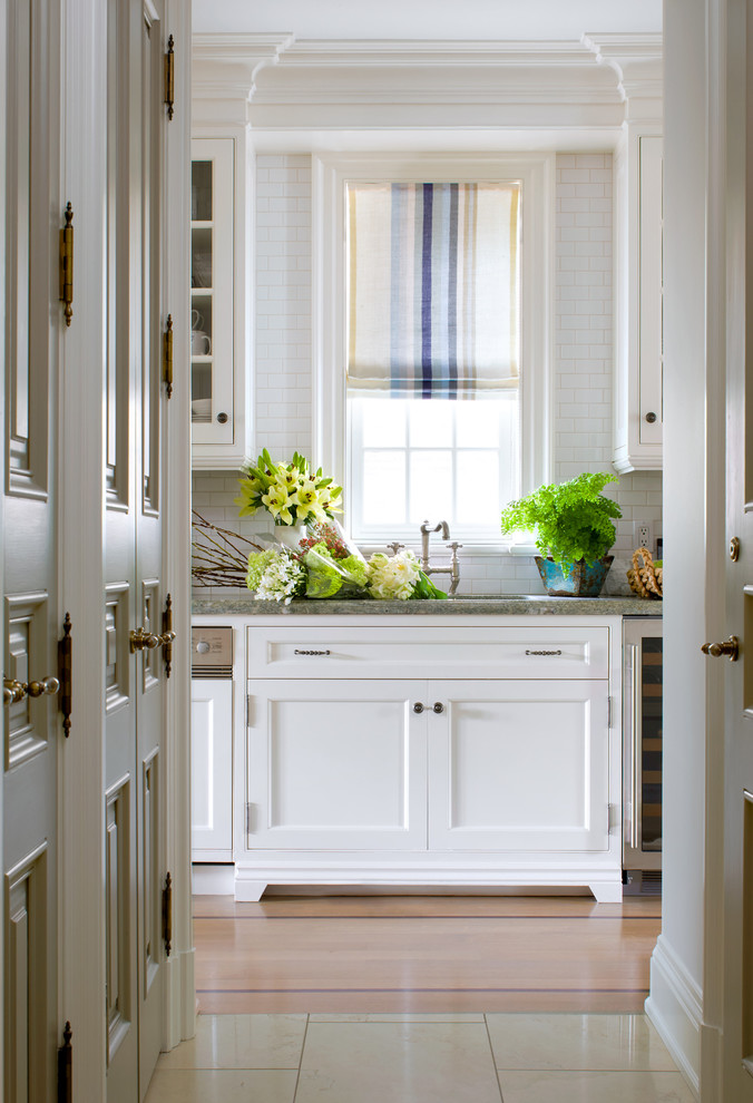 На фото: кухня в классическом стиле с фасадами с утопленной филенкой, белыми фасадами, белым фартуком, фартуком из плитки кабанчик и окном