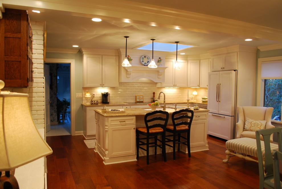 Exempel på ett stort klassiskt kök, med en enkel diskho, släta luckor, vita skåp, granitbänkskiva, vitt stänkskydd, stänkskydd i porslinskakel, integrerade vitvaror, mellanmörkt trägolv och en köksö
