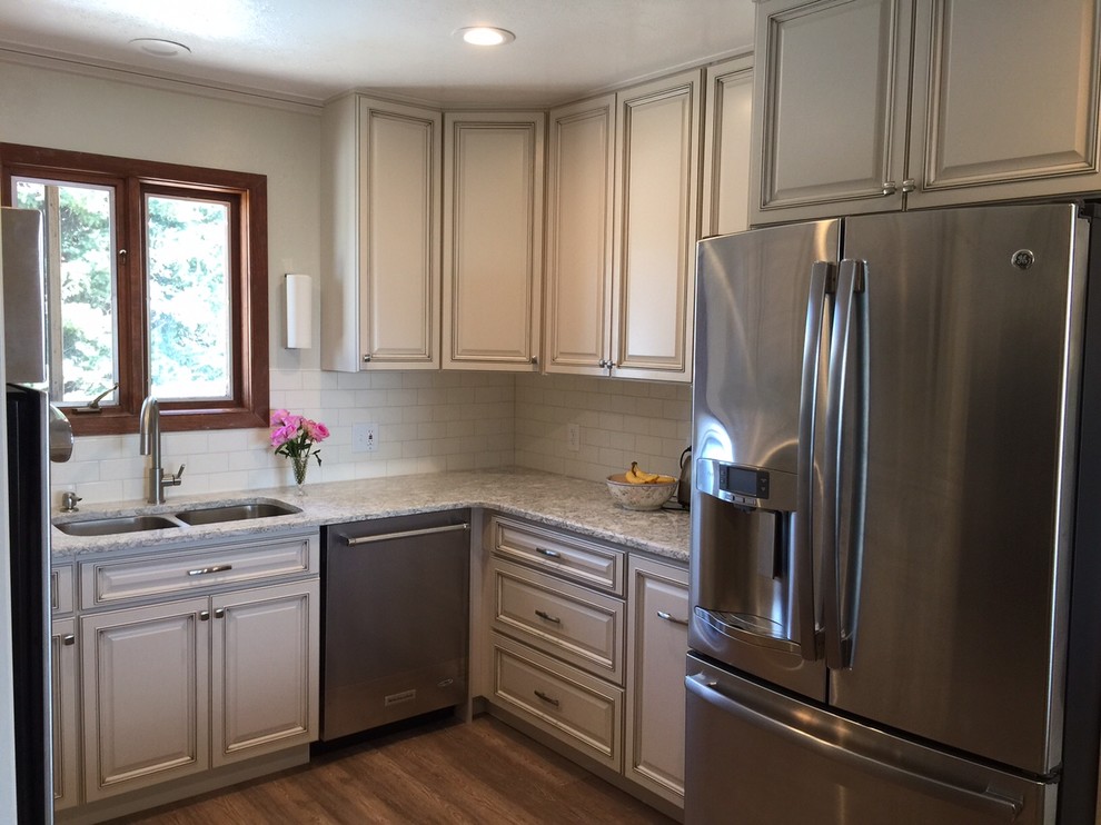 Exempel på ett avskilt, mellanstort klassiskt u-kök, med en undermonterad diskho, luckor med upphöjd panel, vita skåp, bänkskiva i kvarts, vitt stänkskydd, stänkskydd i keramik, rostfria vitvaror och vinylgolv