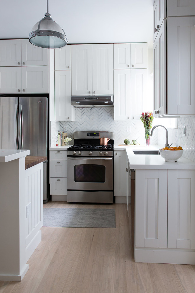 Inspiration för ett vintage l-kök, med en enkel diskho, luckor med infälld panel, vita skåp, grått stänkskydd, rostfria vitvaror, ljust trägolv, en köksö, beiget golv och stänkskydd i marmor