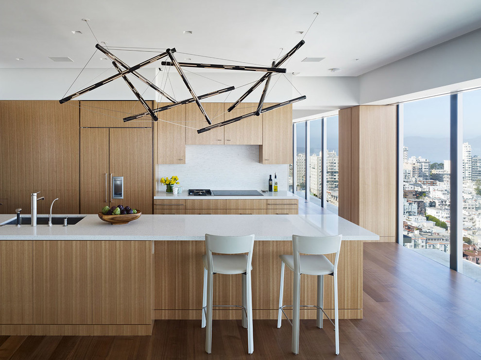 Inspiration for a large modern u-shaped kitchen remodel in San Francisco with an undermount sink, flat-panel cabinets, light wood cabinets, white backsplash, paneled appliances and an island
