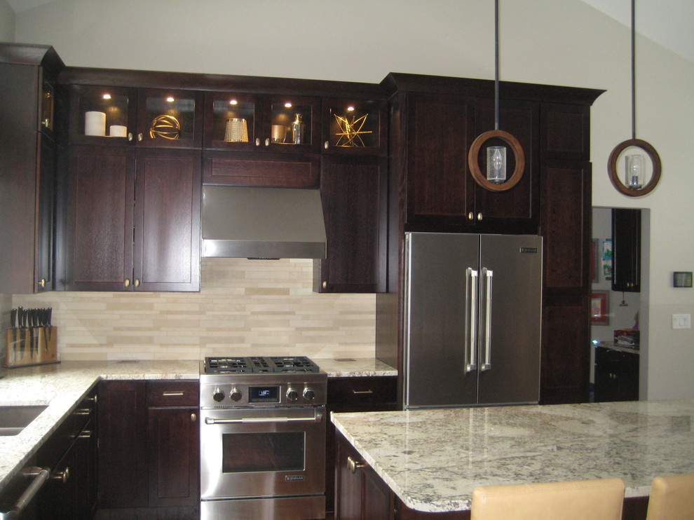 Bild på ett mellanstort rustikt kök, med en dubbel diskho, luckor med infälld panel, skåp i mörkt trä, granitbänkskiva, beige stänkskydd, stänkskydd i stickkakel, rostfria vitvaror, mörkt trägolv och en köksö