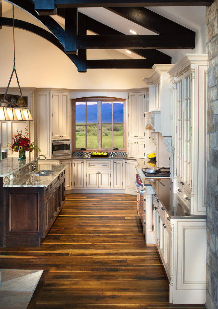 Photo of a rustic l-shaped kitchen in Denver with an island, beaded cabinets, stainless steel appliances and medium hardwood flooring.