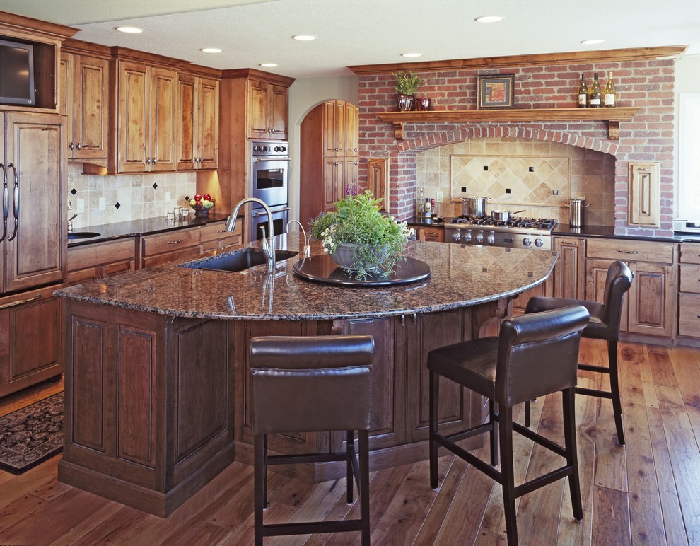 Inspiration for a mid-sized timeless l-shaped medium tone wood floor eat-in kitchen remodel in Denver with a double-bowl sink, raised-panel cabinets, dark wood cabinets, granite countertops, beige backsplash, ceramic backsplash, paneled appliances and an island