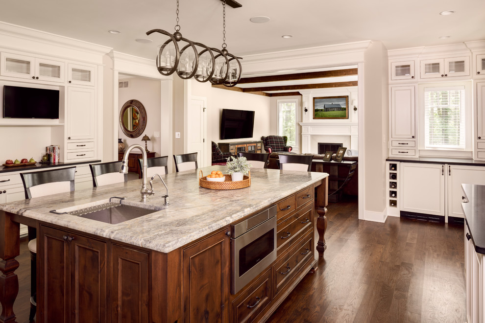 Large farmhouse u-shaped dark wood floor and brown floor eat-in kitchen photo in Milwaukee with a drop-in sink, raised-panel cabinets, brown cabinets, marble countertops, stainless steel appliances and an island