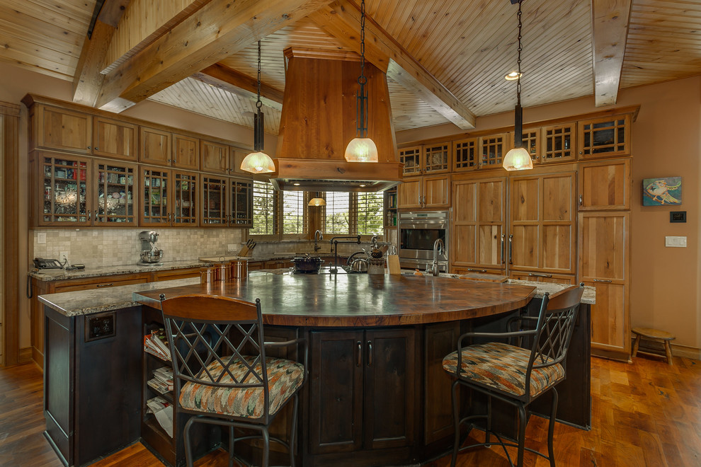 Exemple d'une cuisine montagne en bois brun avec un placard à porte vitrée, une crédence beige, une crédence en mosaïque, un électroménager en acier inoxydable et un sol en bois brun.