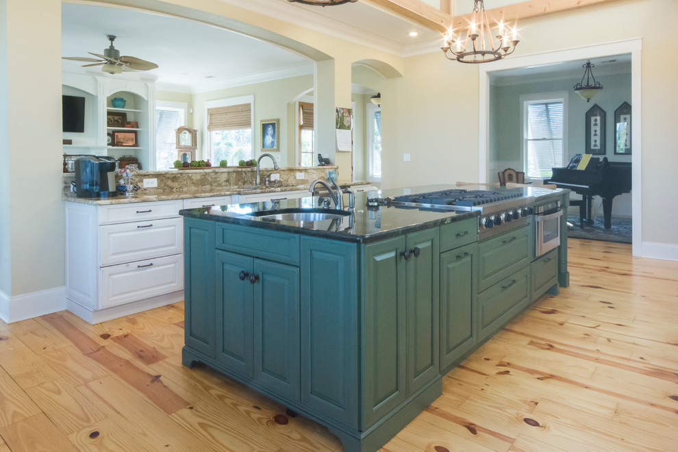 Photo of a large traditional galley kitchen/diner in Charleston with a submerged sink, raised-panel cabinets, white cabinets, granite worktops, stainless steel appliances, light hardwood flooring and an island.