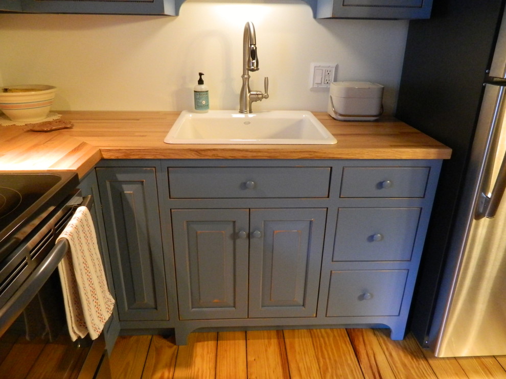 Inspiration pour une petite cuisine américaine chalet en L avec des portes de placard bleues et un plan de travail en bois.