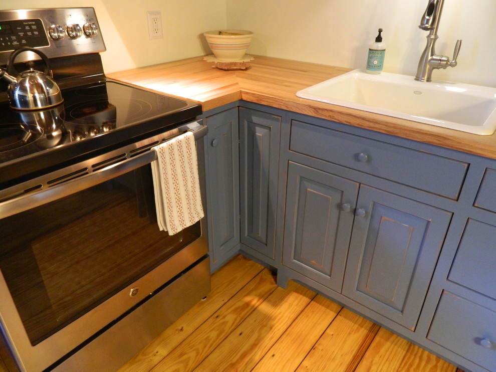 Aménagement d'une petite cuisine américaine montagne en L avec des portes de placard bleues et un plan de travail en bois.