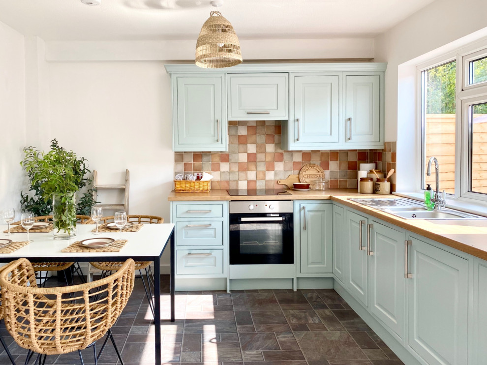 Inspiration for a medium sized farmhouse l-shaped kitchen/diner in Gloucestershire with a built-in sink, shaker cabinets, blue cabinets, wood worktops, multi-coloured splashback, ceramic splashback, stainless steel appliances, lino flooring, no island, grey floors and beige worktops.