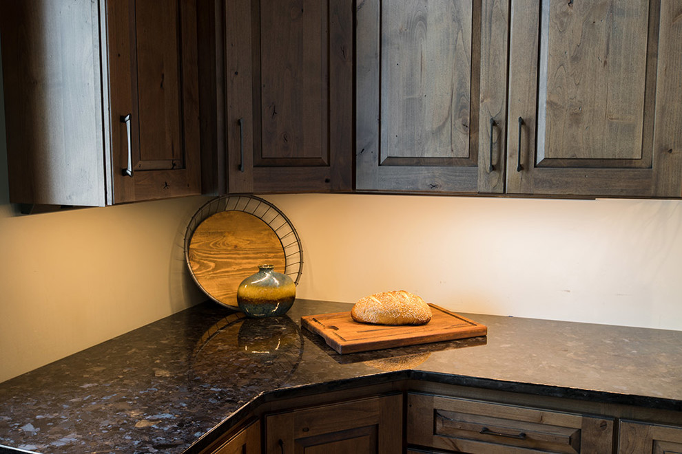 Inspiration pour une cuisine chalet en bois vieilli avec un placard avec porte à panneau surélevé, un plan de travail en granite et plan de travail noir.