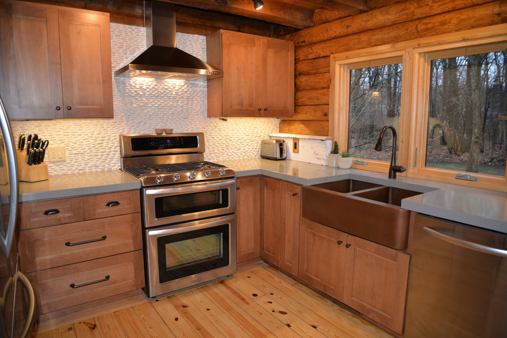 Inredning av ett rustikt mellanstort kök, med en undermonterad diskho, luckor med infälld panel, skåp i mellenmörkt trä, bänkskiva i koppar, vitt stänkskydd, rostfria vitvaror, ljust trägolv och en köksö