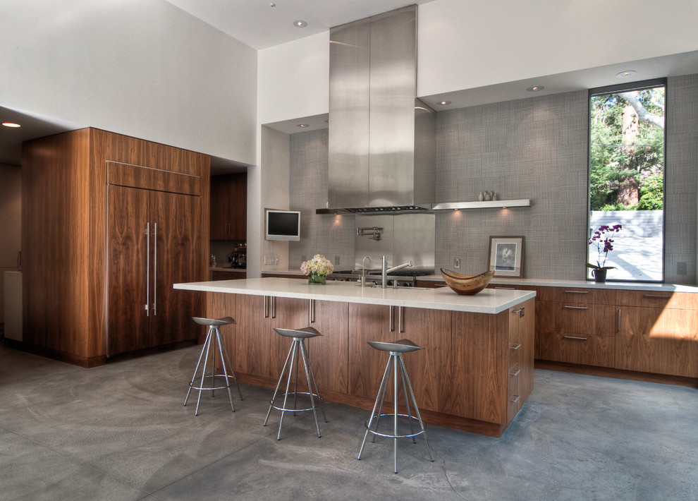 Moderne Wohnküche mit flächenbündigen Schrankfronten, dunklen Holzschränken, Elektrogeräten mit Frontblende, Kücheninsel und weißer Arbeitsplatte in Los Angeles