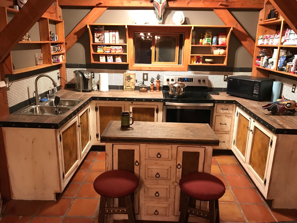アルバカーキにあるお手頃価格の小さなラスティックスタイルのおしゃれなキッチン (ドロップインシンク、白いキャビネット、タイルカウンター、白いキッチンパネル、モザイクタイルのキッチンパネル、シルバーの調理設備、テラコッタタイルの床、オレンジの床、茶色いキッチンカウンター) の写真