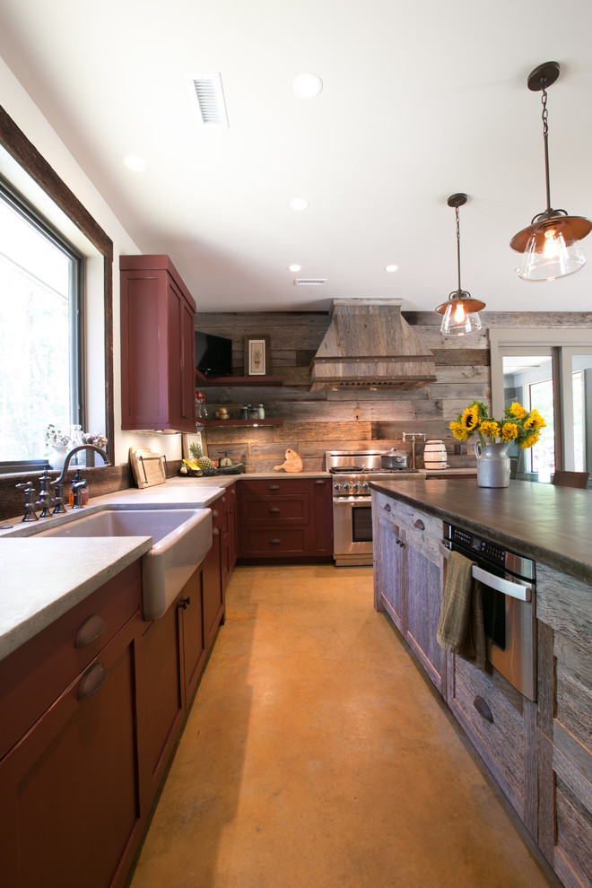 This is an example of a rustic u-shaped kitchen/diner in Charleston with a belfast sink, shaker cabinets, distressed cabinets, concrete worktops, stainless steel appliances, concrete flooring and an island.