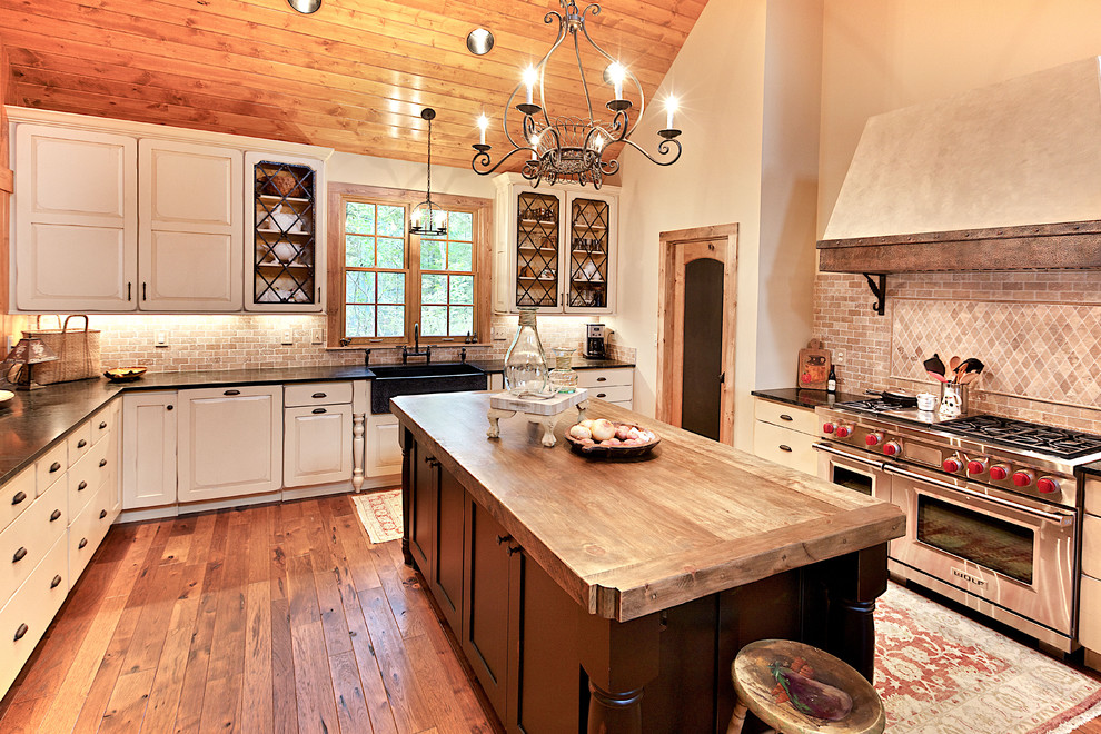 Exempel på ett avskilt, stort lantligt u-kök, med luckor med upphöjd panel, vita skåp, träbänkskiva, rött stänkskydd, en köksö, en rustik diskho, integrerade vitvaror, mörkt trägolv och stänkskydd i travertin
