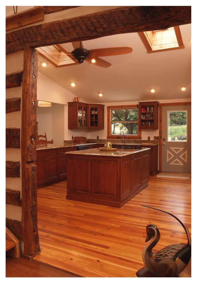 Example of a mid-sized mountain style u-shaped light wood floor enclosed kitchen design in Baltimore with raised-panel cabinets, medium tone wood cabinets, granite countertops, gray backsplash, stone slab backsplash, black appliances, an island and an undermount sink