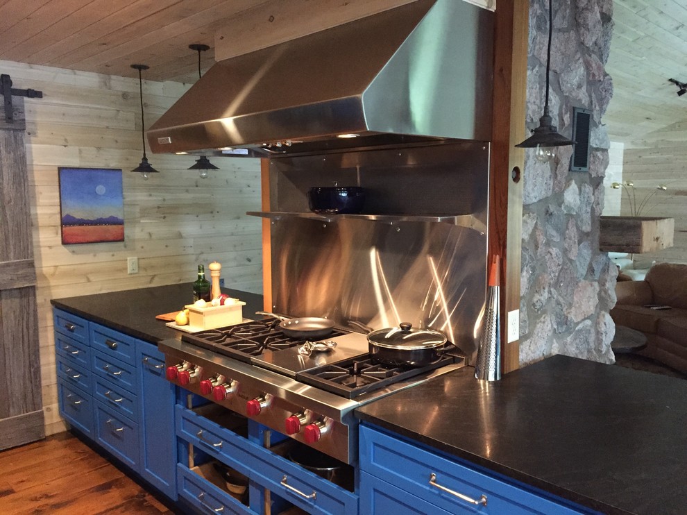 Idéer för ett stort rustikt kök, med en rustik diskho, luckor med glaspanel, blå skåp, granitbänkskiva, stänkskydd i trä, rostfria vitvaror, mellanmörkt trägolv och en köksö