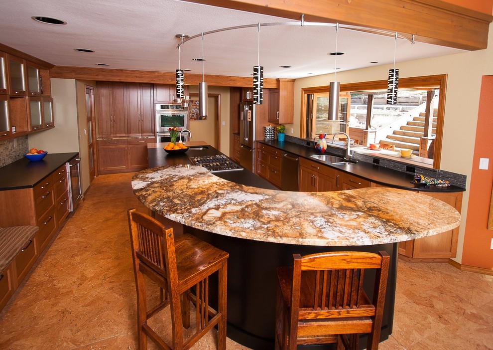 Foto på ett stort rustikt kök, med en dubbel diskho, luckor med infälld panel, skåp i ljust trä, bänkskiva i täljsten, stänkskydd i stickkakel, rostfria vitvaror och flera köksöar