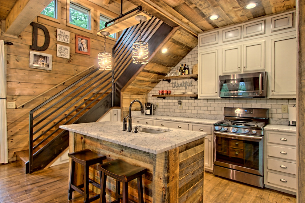 Idéer för ett litet rustikt kök med öppen planlösning, med en nedsänkt diskho, luckor med infälld panel, skåp i slitet trä, granitbänkskiva, vitt stänkskydd, stänkskydd i stenkakel, rostfria vitvaror, målat trägolv, en köksö och brunt golv