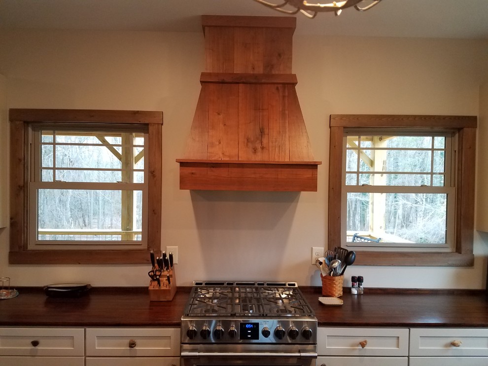 This is an example of a medium sized rustic l-shaped kitchen in Other with a double-bowl sink, flat-panel cabinets, beige cabinets, wood worktops, wood splashback, stainless steel appliances, bamboo flooring and brown floors.