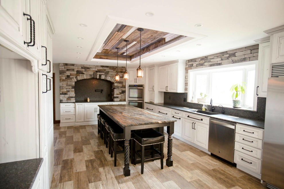 Foto de cocina rústica grande con armarios con paneles con relieve, puertas de armario con efecto envejecido, encimera de granito y una isla