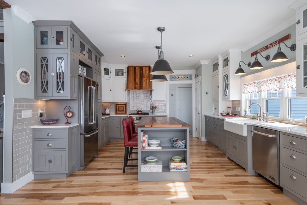 Foto på ett avskilt lantligt vit kök, med en rustik diskho, grå skåp, grått stänkskydd, rostfria vitvaror, ljust trägolv och en köksö