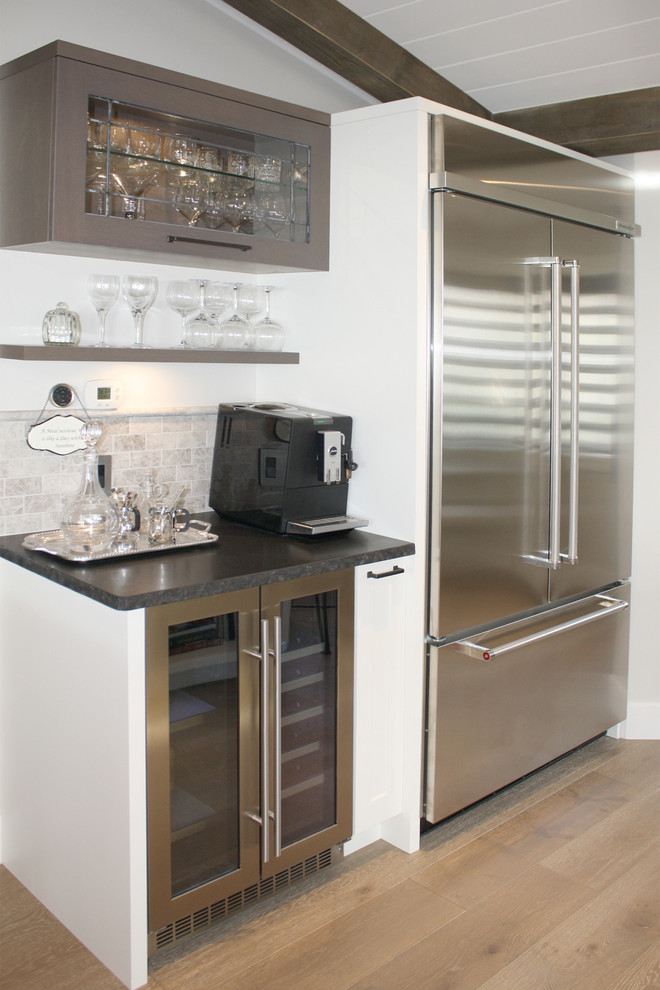 Bild på ett mellanstort rustikt kök, med en undermonterad diskho, skåp i shakerstil, vita skåp, granitbänkskiva, grått stänkskydd, stänkskydd i stenkakel, rostfria vitvaror, mellanmörkt trägolv och en halv köksö