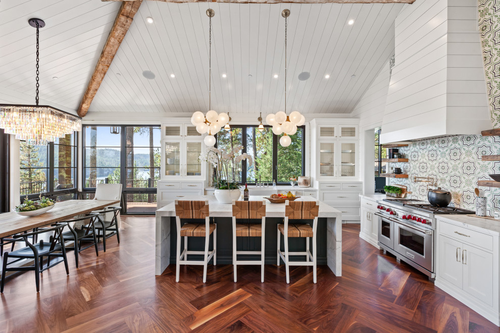 Exempel på ett klassiskt vit vitt l-kök, med en rustik diskho, luckor med infälld panel, vita skåp, flerfärgad stänkskydd, rostfria vitvaror, mörkt trägolv, en köksö och brunt golv