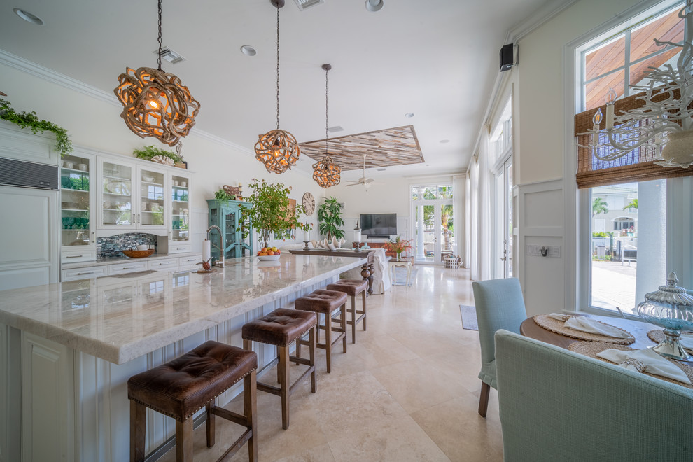 Example of a large beach style l-shaped marble floor and beige floor open concept kitchen design in Miami with an undermount sink, raised-panel cabinets, white cabinets, quartzite countertops, blue backsplash, glass tile backsplash, an island and white countertops