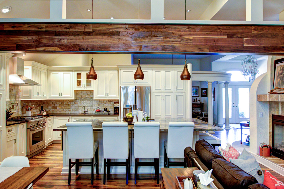 Example of a large mountain style l-shaped medium tone wood floor eat-in kitchen design in Kansas City with an undermount sink, recessed-panel cabinets, white cabinets, granite countertops, stone slab backsplash, stainless steel appliances and an island
