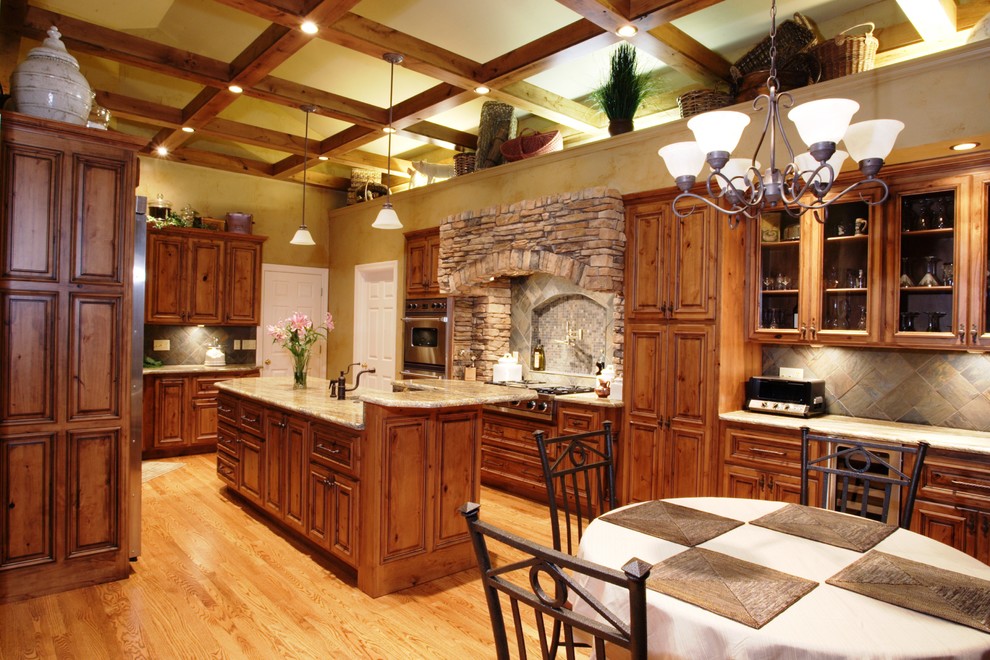Inspiration for a rustic eat-in kitchen remodel in St Louis with an undermount sink, raised-panel cabinets, medium tone wood cabinets, granite countertops and stainless steel appliances