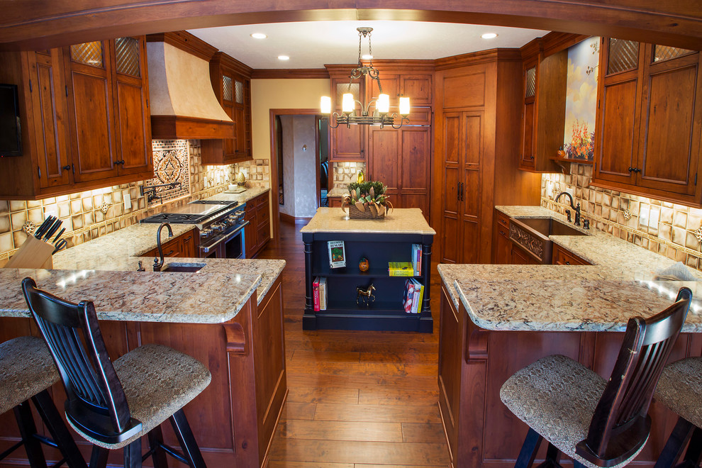 Example of a classic u-shaped eat-in kitchen design in Cleveland with a farmhouse sink, recessed-panel cabinets, medium tone wood cabinets, quartz countertops, beige backsplash and stainless steel appliances