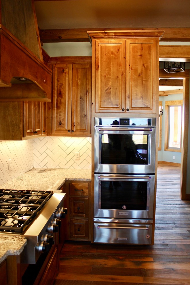 Idéer för att renovera ett stort lantligt vit vitt kök, med en rustik diskho, luckor med upphöjd panel, skåp i mellenmörkt trä, granitbänkskiva, vitt stänkskydd, stänkskydd i keramik, rostfria vitvaror, mellanmörkt trägolv, flera köksöar och brunt golv