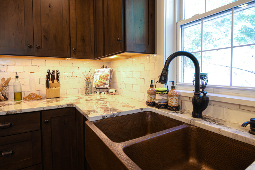 Rustik inredning av ett avskilt, mellanstort vit vitt l-kök, med en rustik diskho, skåp i shakerstil, skåp i mörkt trä, granitbänkskiva, vitt stänkskydd, stänkskydd i keramik, rostfria vitvaror, vinylgolv, en köksö och brunt golv