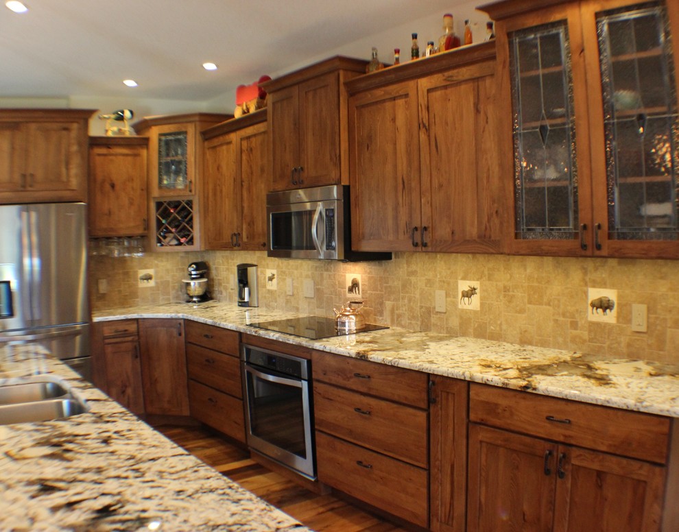 Example of a large mountain style l-shaped light wood floor open concept kitchen design in Chicago with an undermount sink, flat-panel cabinets, medium tone wood cabinets, granite countertops, beige backsplash, ceramic backsplash, stainless steel appliances and an island