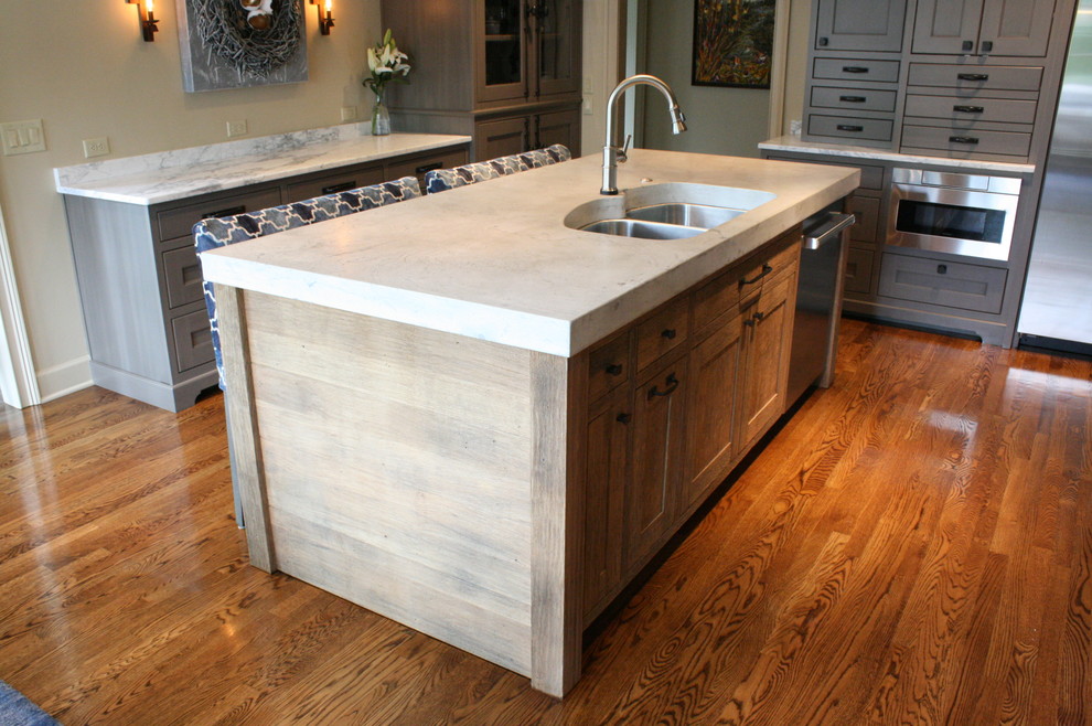 Example of an eclectic medium tone wood floor and brown floor kitchen design in Nashville with an undermount sink, flat-panel cabinets, distressed cabinets, concrete countertops and stainless steel appliances
