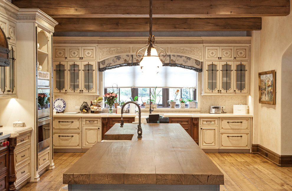 Bild på ett mycket stort rustikt brun brunt kök, med luckor med upphöjd panel, vita skåp, en köksö, en rustik diskho, träbänkskiva, beige stänkskydd, stänkskydd i mosaik, rostfria vitvaror, målat trägolv och gult golv