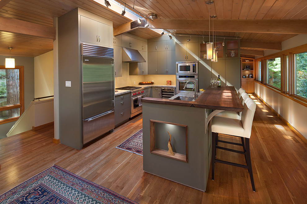 Mid-sized trendy l-shaped eat-in kitchen photo in San Francisco with a single-bowl sink, flat-panel cabinets, green cabinets, stainless steel appliances and an island