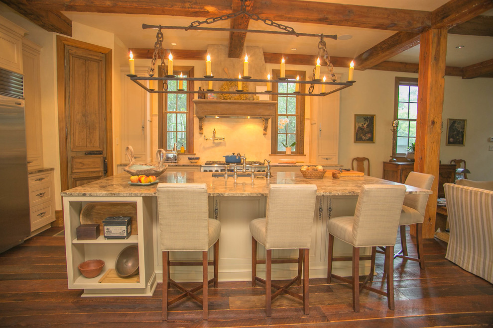 Foto på ett stort rustikt l-kök, med en enkel diskho, luckor med infälld panel, skåp i slitet trä, marmorbänkskiva, rostfria vitvaror, mörkt trägolv och en köksö
