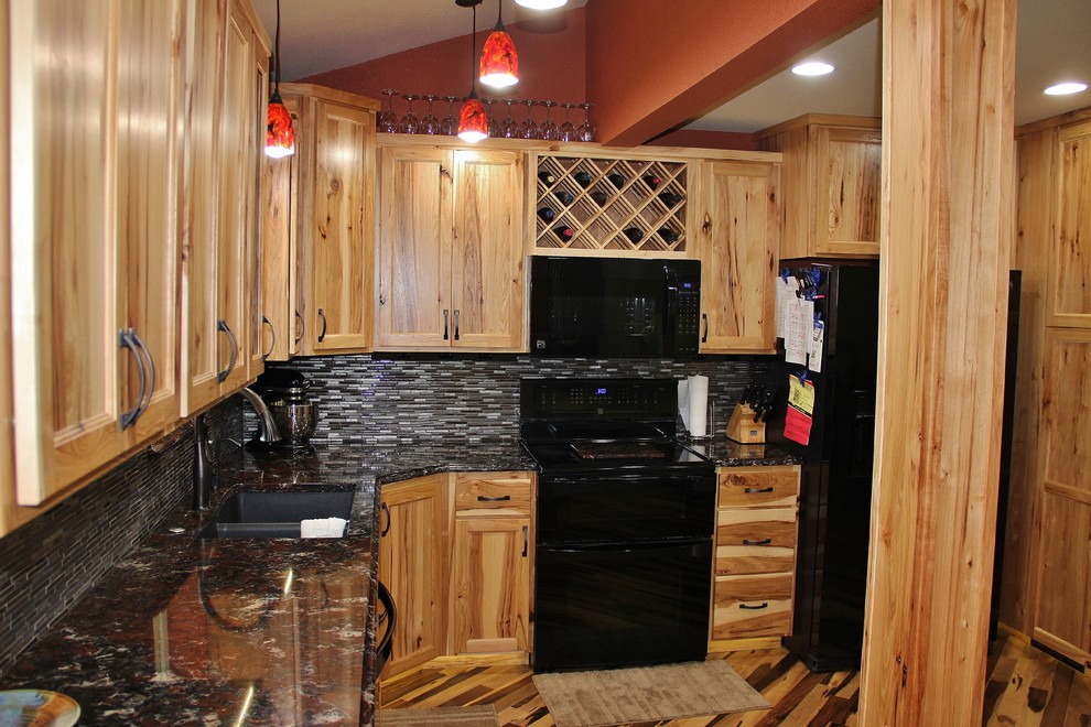 Photo of a large rustic l-shaped kitchen/diner in Minneapolis with a submerged sink, flat-panel cabinets, light wood cabinets, engineered stone countertops, metallic splashback, glass tiled splashback, black appliances, medium hardwood flooring and no island.