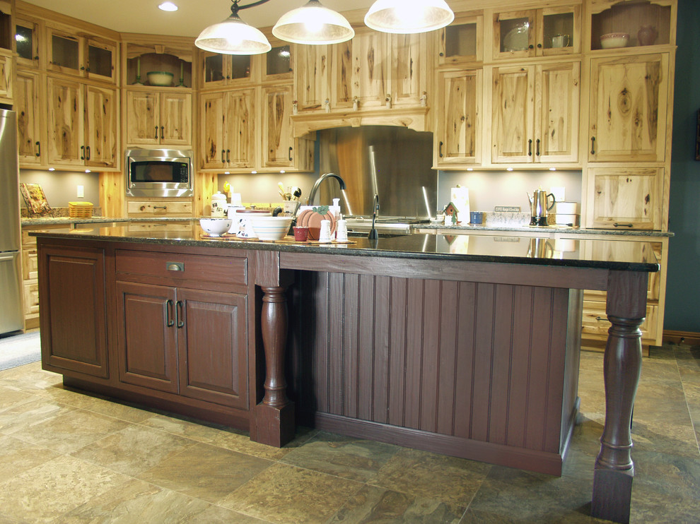 Cette image montre une cuisine chalet en bois vieilli avec un placard avec porte à panneau surélevé, un plan de travail en granite et îlot.