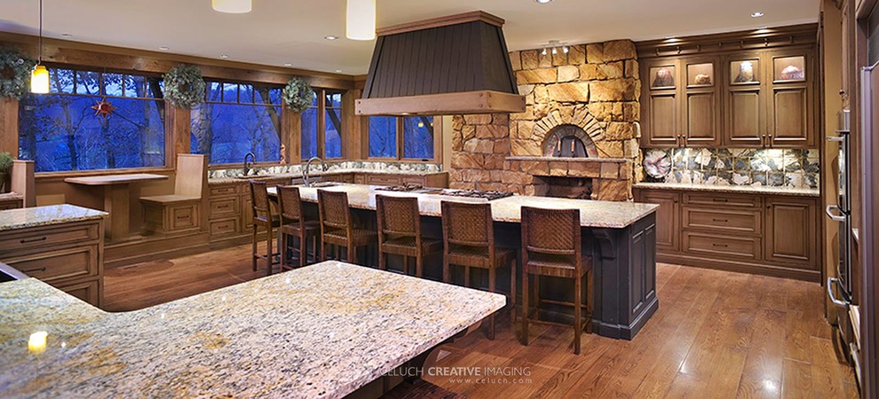 Mountain style eat-in kitchen photo in Columbus with a farmhouse sink, raised-panel cabinets, medium tone wood cabinets, granite countertops, multicolored backsplash and stainless steel appliances