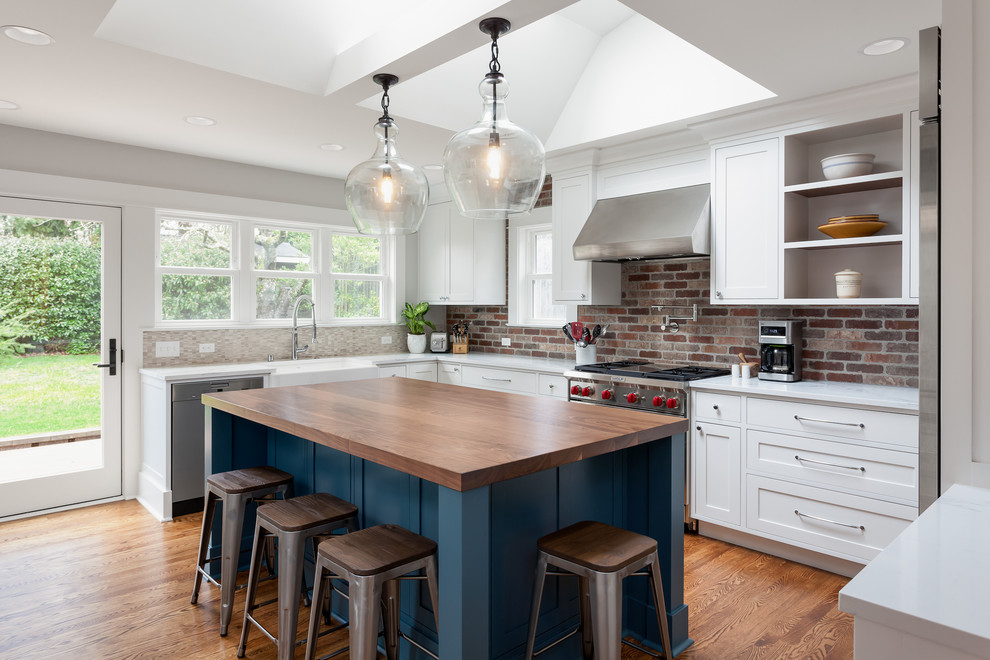 Example of a huge trendy u-shaped medium tone wood floor open concept kitchen design in Seattle with a farmhouse sink, shaker cabinets, white cabinets, quartzite countertops, red backsplash, brick backsplash, stainless steel appliances and an island