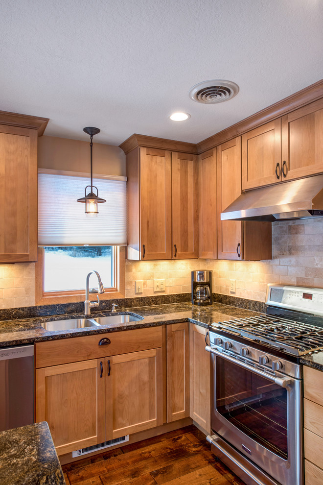 Inspiration for a mid-sized timeless l-shaped medium tone wood floor eat-in kitchen remodel in Minneapolis with an undermount sink, shaker cabinets, medium tone wood cabinets, granite countertops, beige backsplash, stone tile backsplash, stainless steel appliances and an island